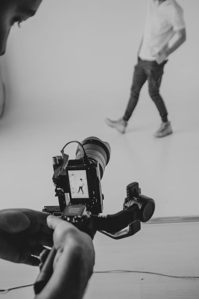 Cinematographer recording model in studio using DSLR camera and stabilizer.