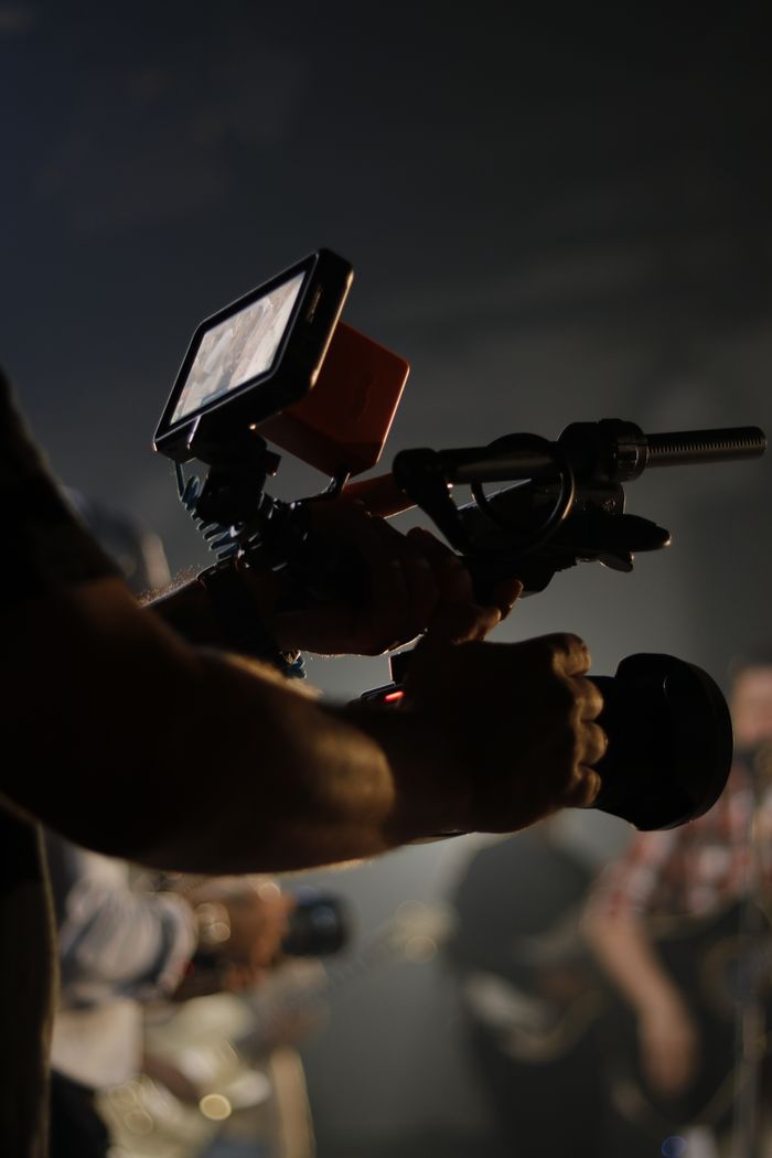 Silhouette of a person filming with a Canon DSLR camera during a live event.